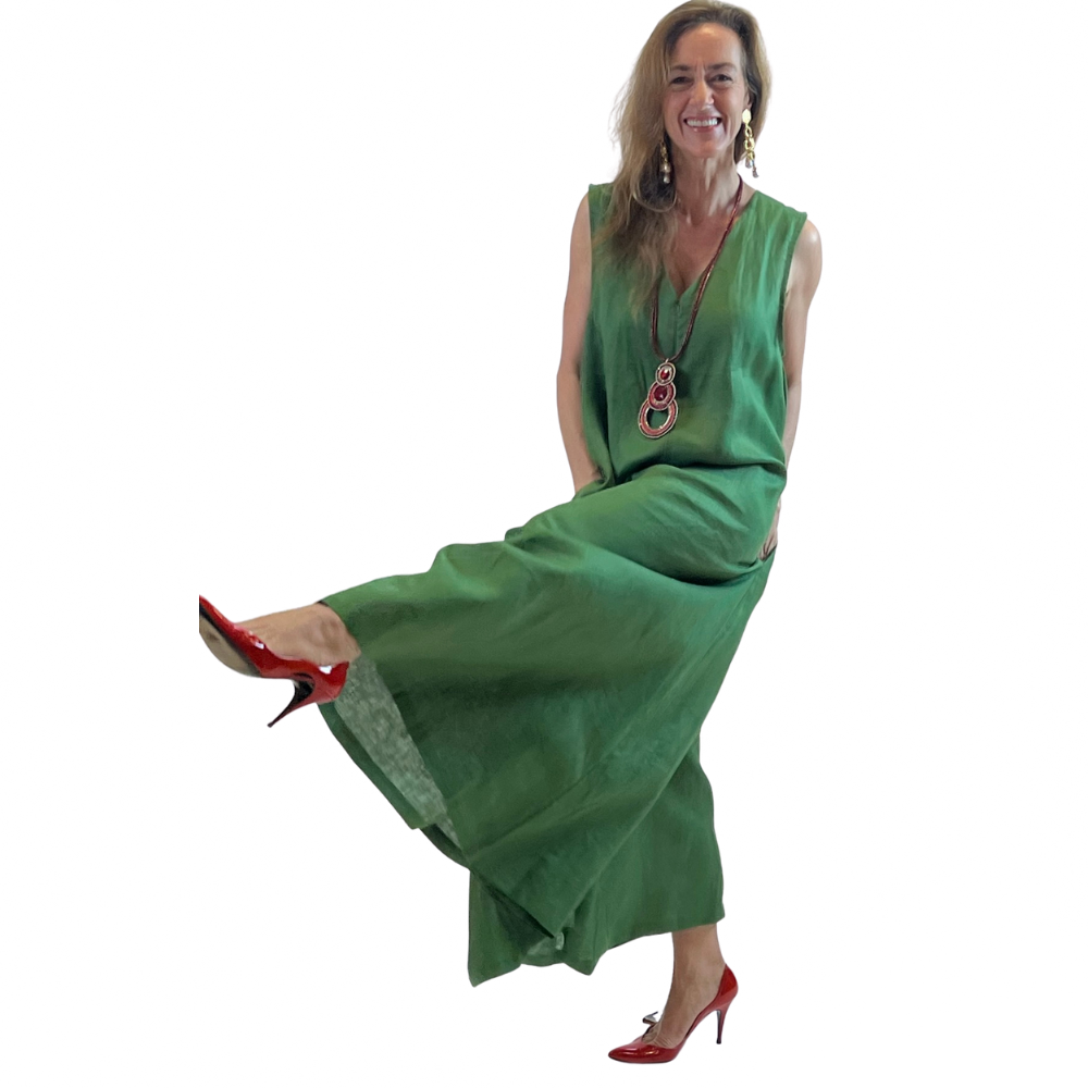 Model wearing a green sleeveless linen romper with a maxi-length flow, pockets, and back zipper